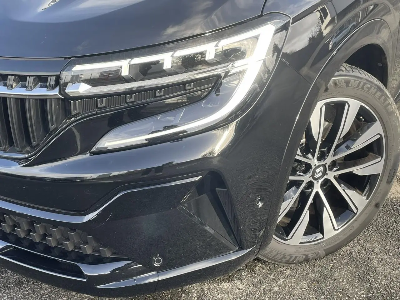 Gros plan sur l'avant droit du Renault Espace noir étoilé, mettant en valeur le phare LED et la jante alliage 19 pouces.