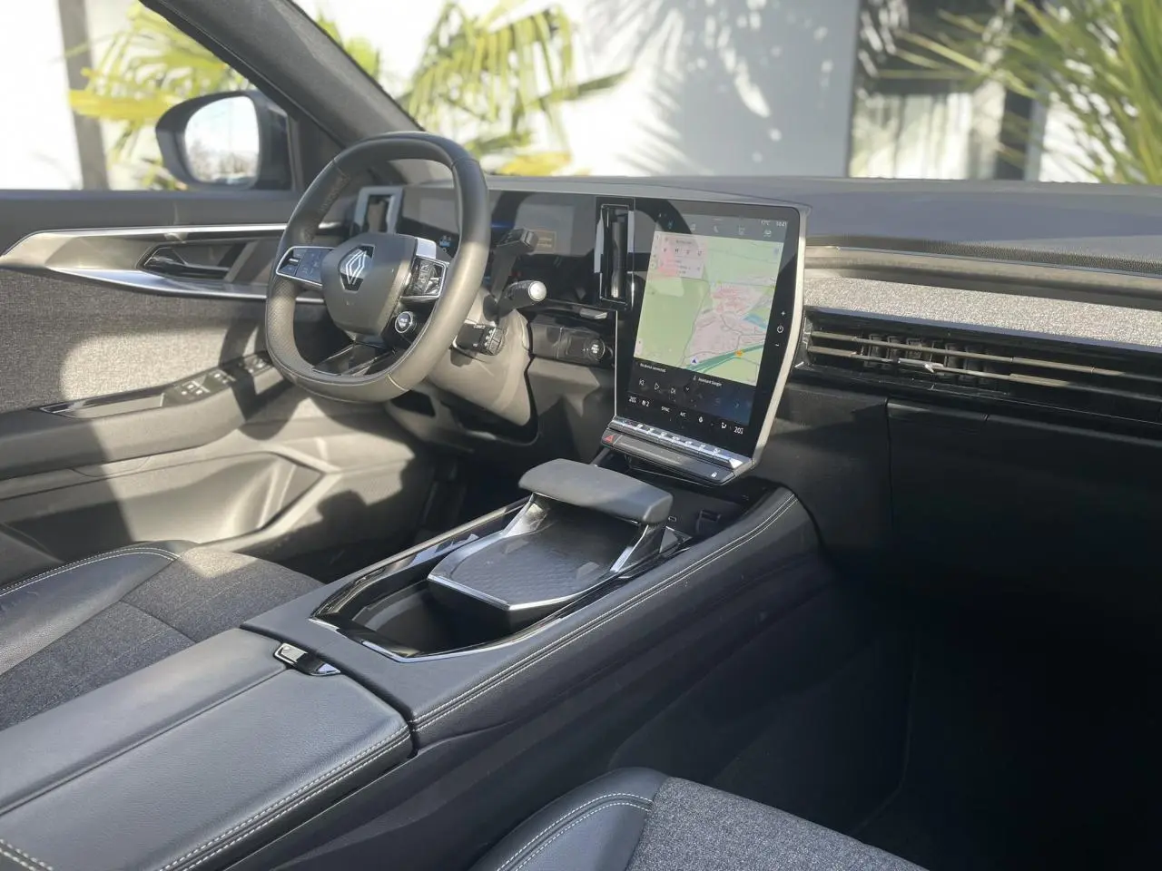 Vue intérieure côté conducteur du Renault Espace 2024, avec volant multifonction, écran tactile vertical et sellerie grise.