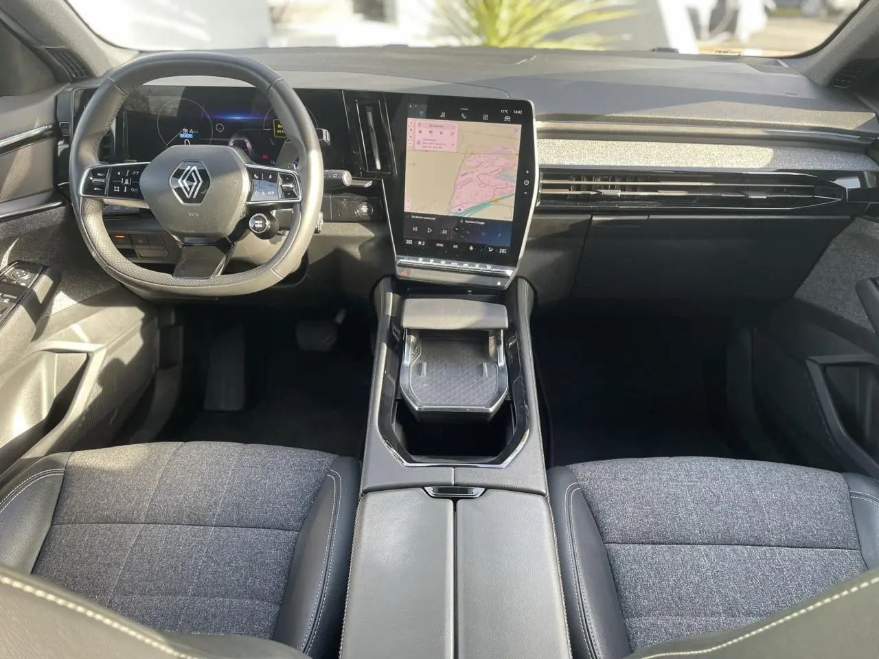 Vue intérieure avant du Renault Espace 2024, tableau de bord noir avec grand écran tactile vertical et volant multifonction.