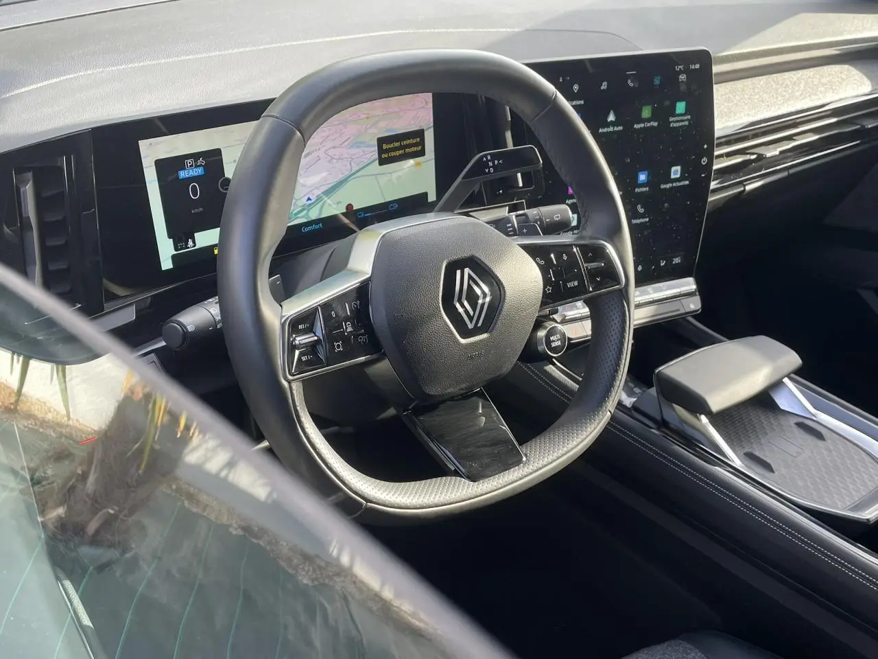 Vue intérieure du poste de conduite Renault Espace 2024, volant multifonction et grand écran tactile noir.