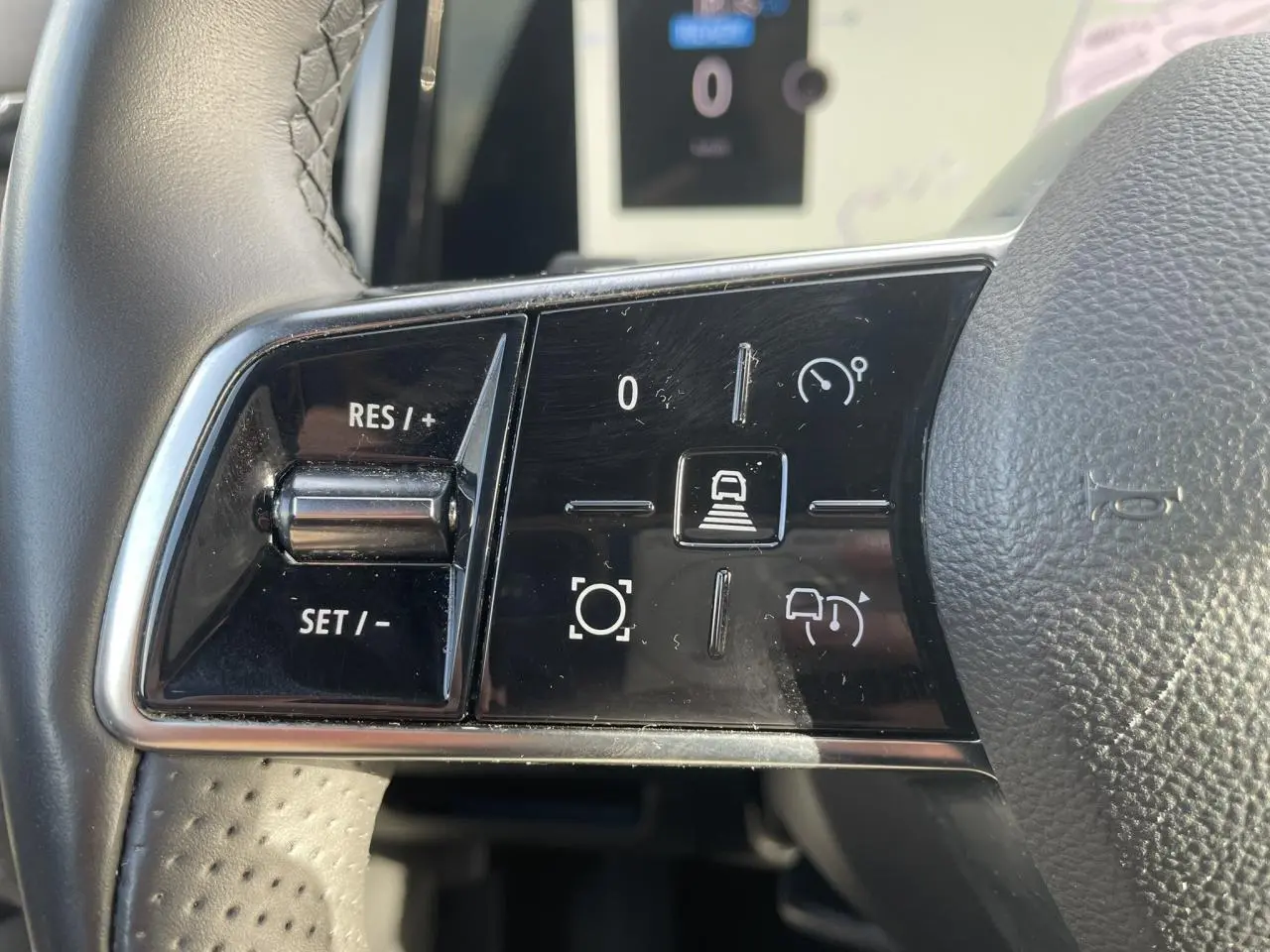 Gros plan sur les commandes de régulateur de vitesse au volant noir du Renault Espace 2024 E-Tech Full Hybrid.