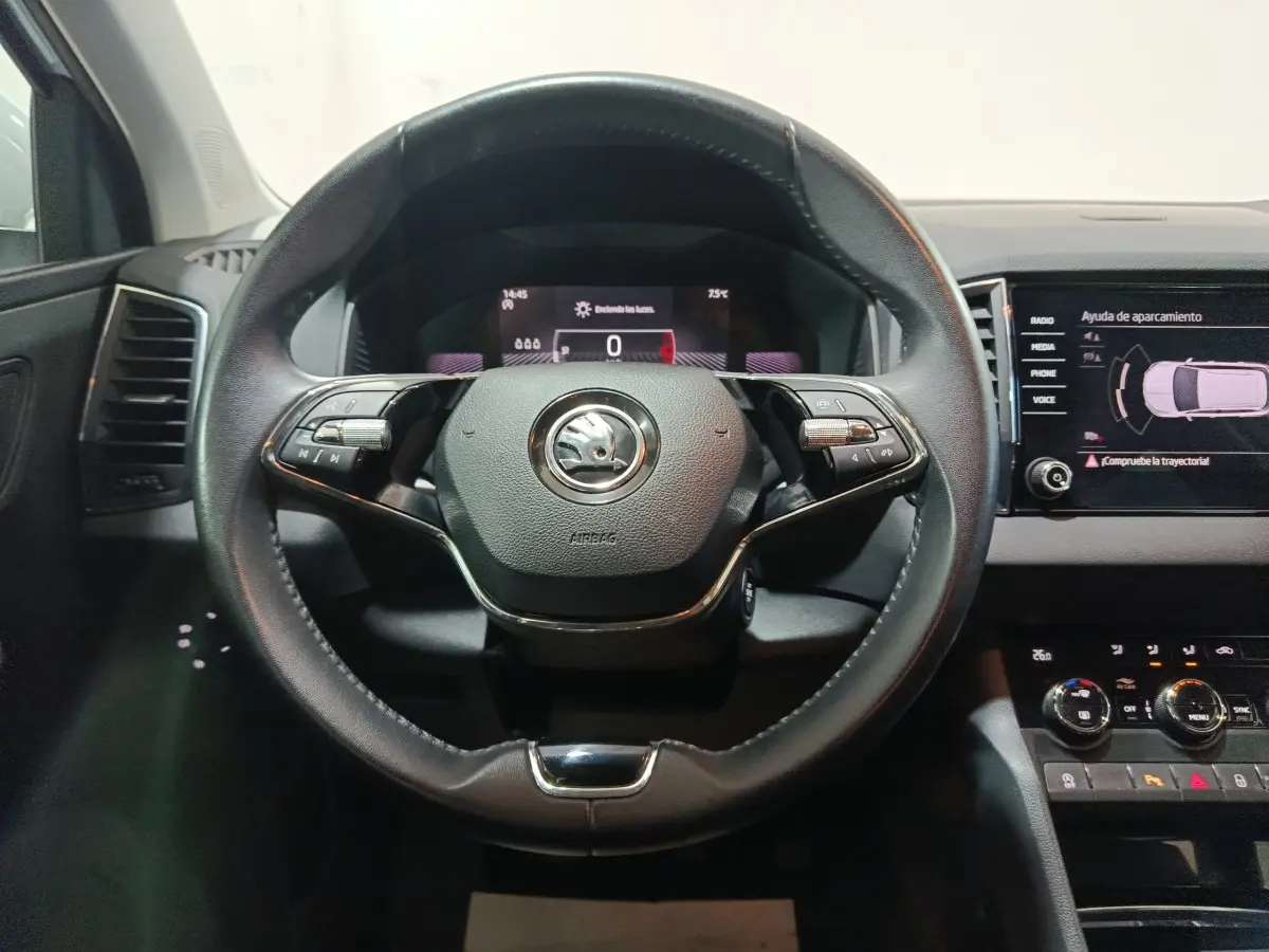 Vue intérieure centrée sur le volant cuir noir du Skoda Karoq 2024 avec tableau de bord digital et écran tactile latéral.