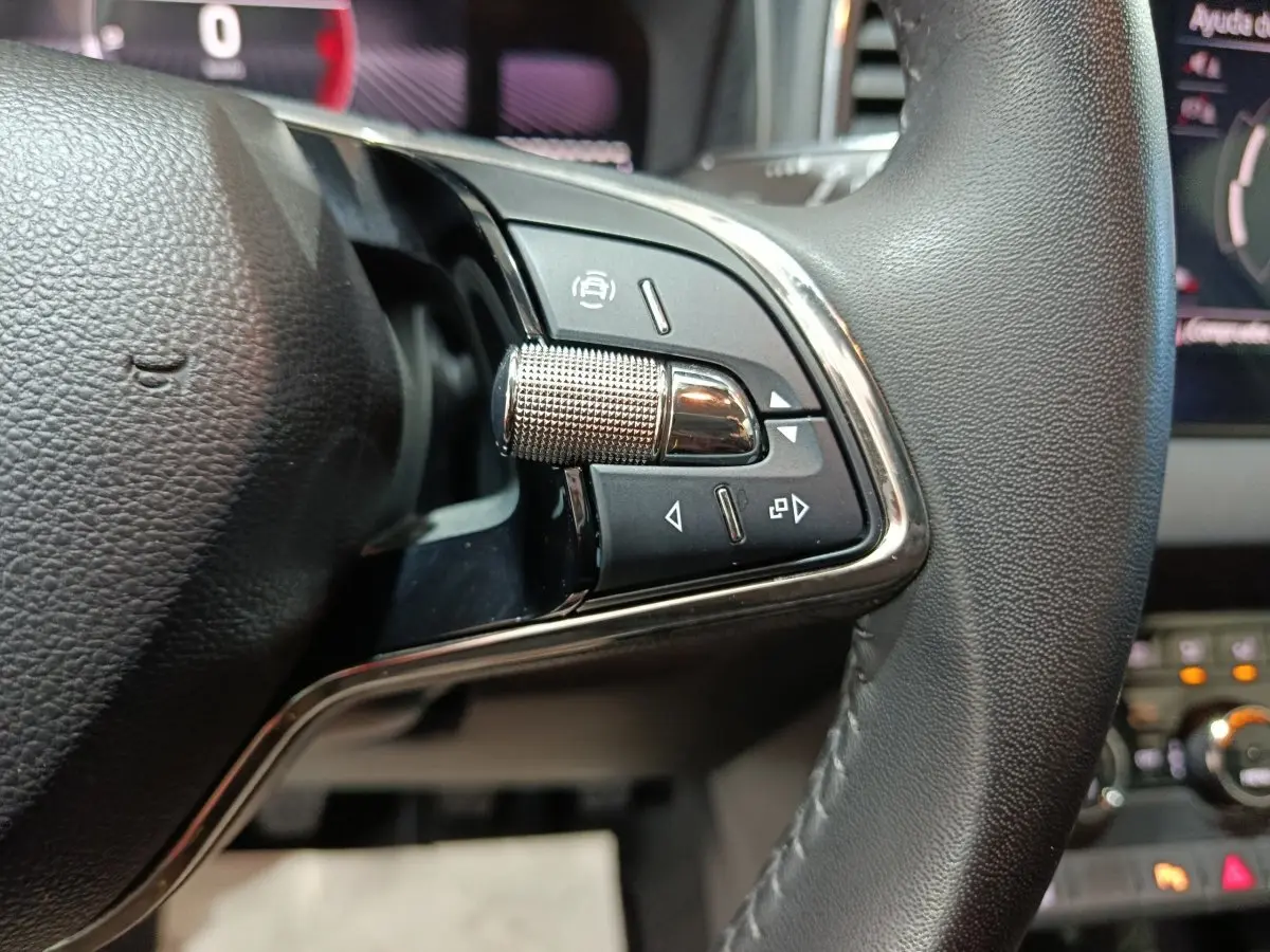 Gros plan sur les commandes gauche du volant cuir noir du Skoda Karoq 2024 avec écran digital en arrière-plan.