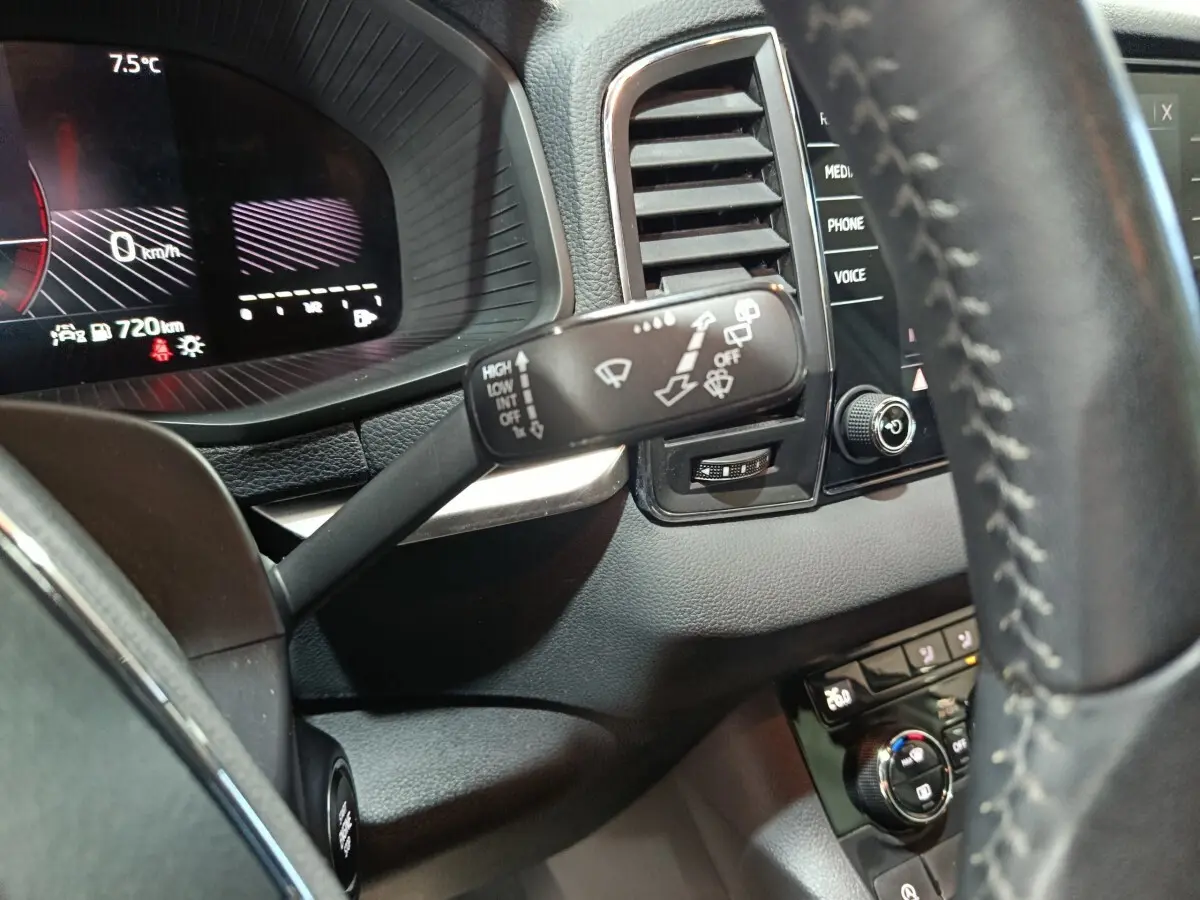 Gros plan sur le combiné d'instruments et la commande d'essuie-glace à gauche du volant cuir dans un Skoda Karoq blanc 2024.