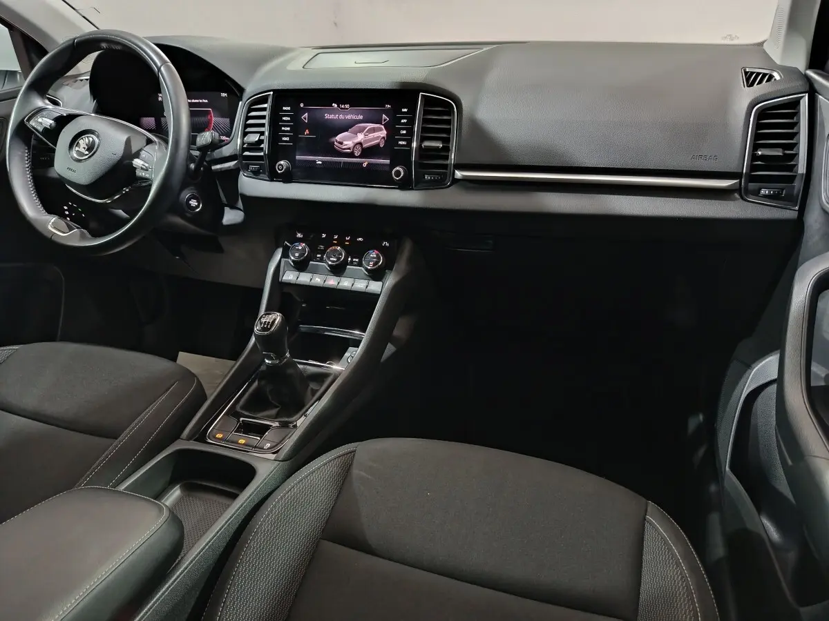 Intérieur noir du Skoda Karoq 2024, vue de face côté conducteur avec tableau de bord et écran tactile central.