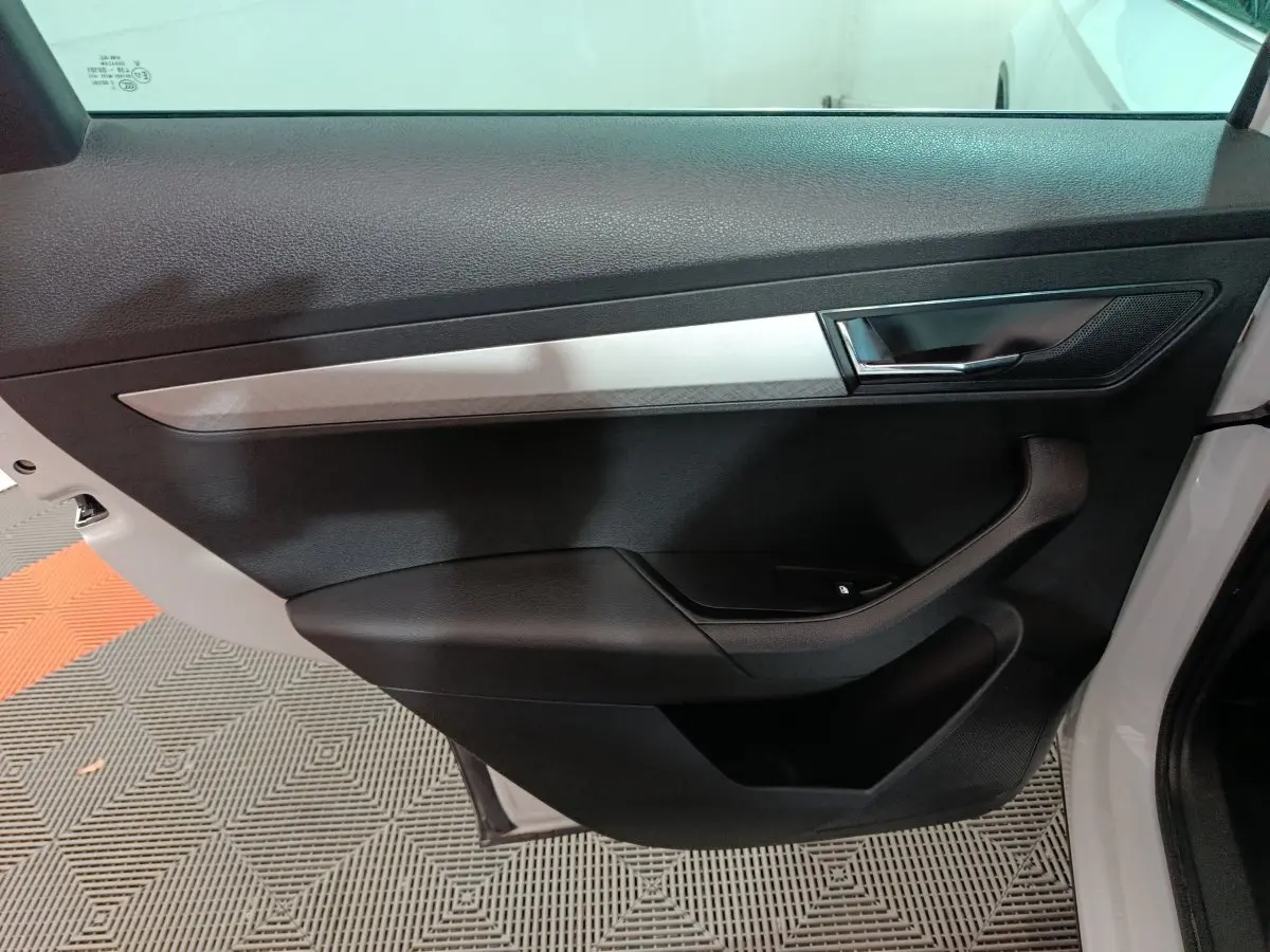 Vue rapprochée de la porte intérieure côté gauche blanche du Skoda Karoq 2024 avec poignée et insert argenté.