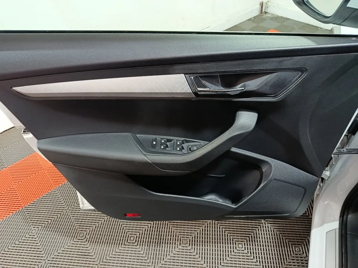 Vue intérieure sur la porte avant gauche noire avec insert argenté du Skoda Karoq blanc 2024.