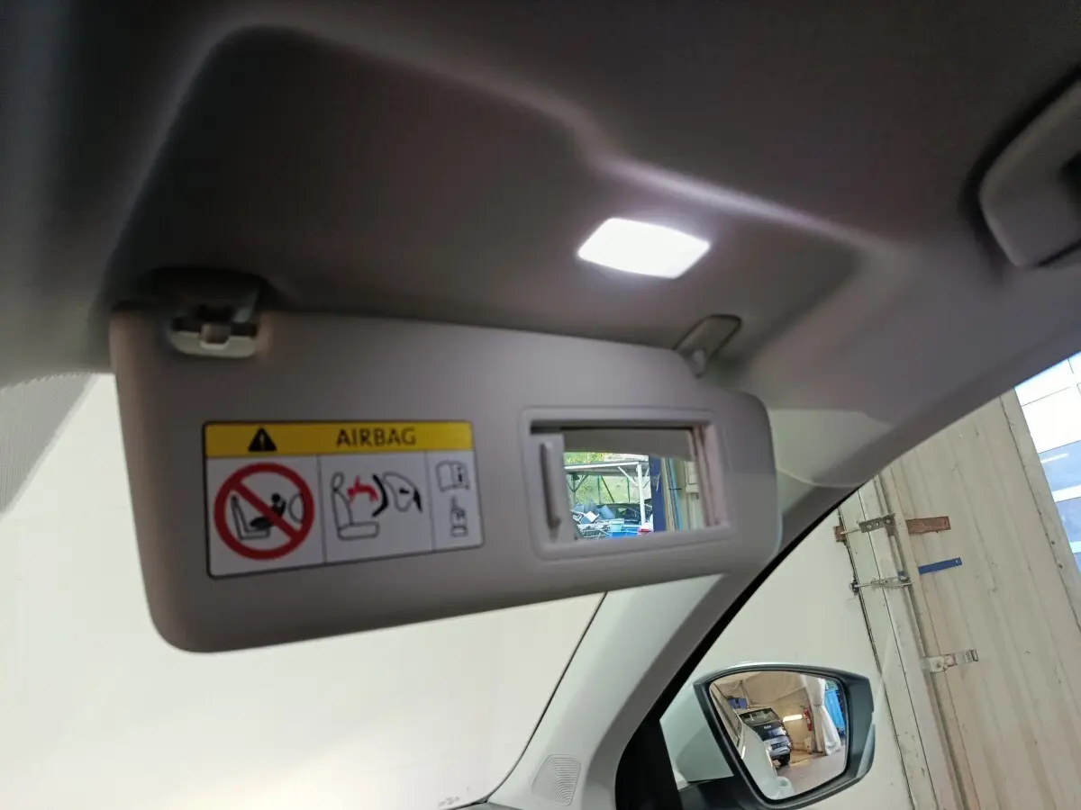 Vue intérieure du pare-soleil côté conducteur avec miroir éclairé et rétroviseur extérieur droit d’un Skoda Karoq blanc 2024.