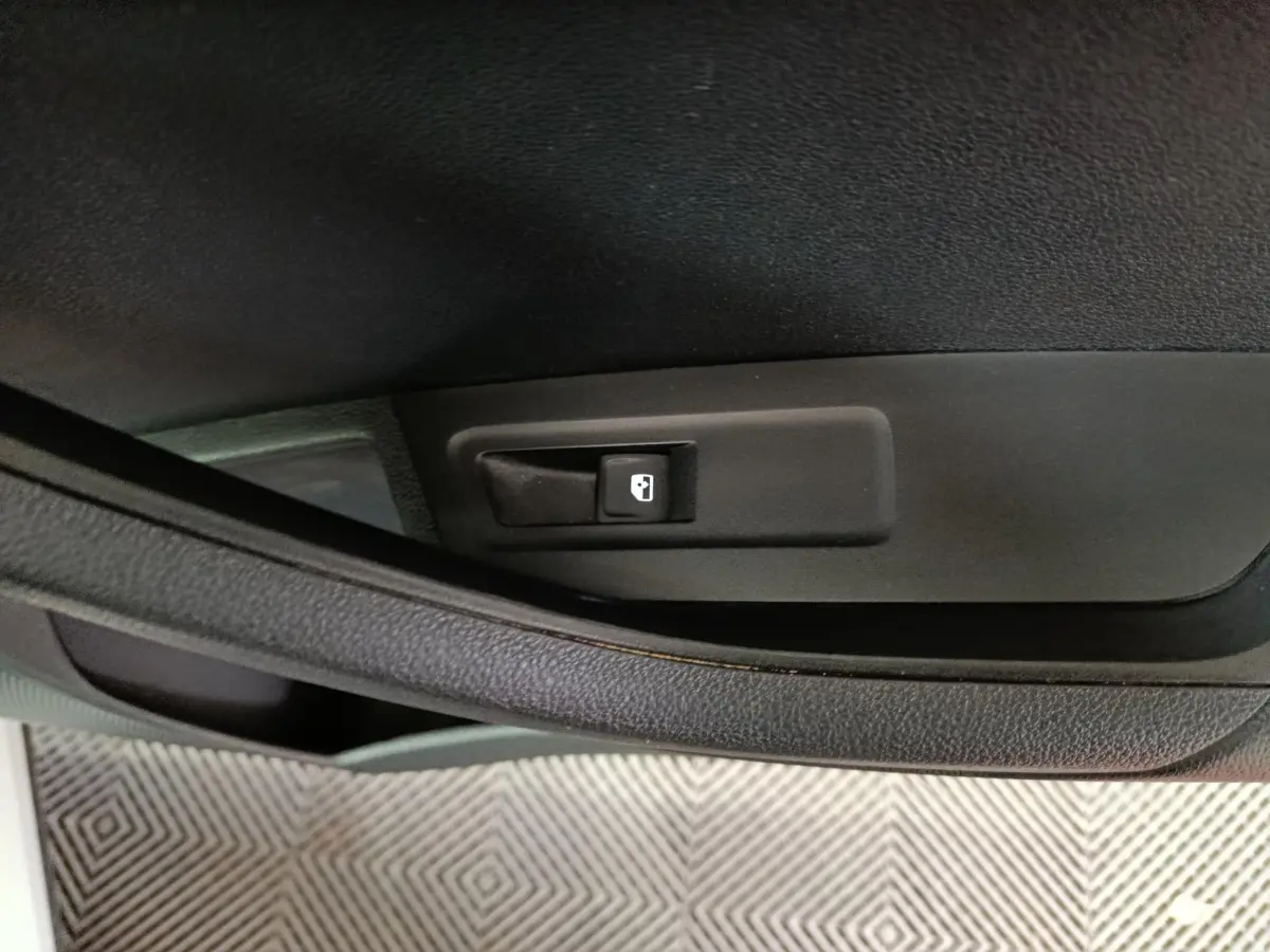 Gros plan sur la commande d'ouverture de trappe à carburant noire dans l'habitacle du Skoda Karoq blanc 2024.