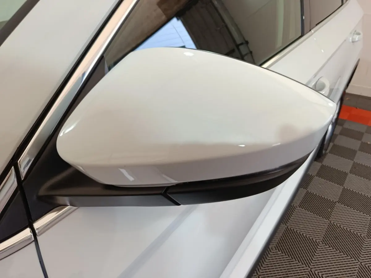 Rétroviseur droit blanc du Skoda Karoq 2.0 TDI 2024, vue rapprochée sur la carrosserie blanche et poignée de porte.