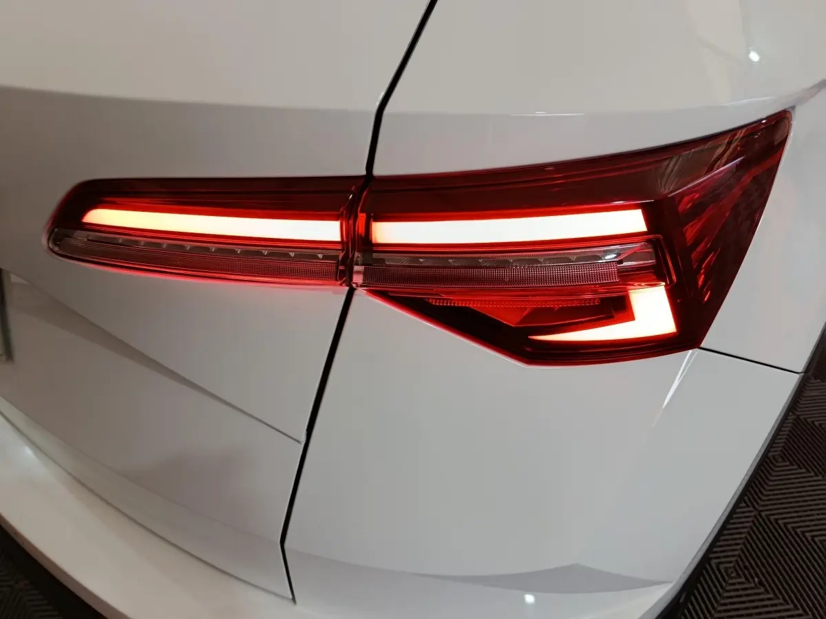 Gros plan sur le feu arrière droit allumé d’un Skoda Karoq blanc, soulignant les lignes nettes de la carrosserie.