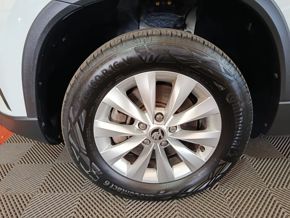 Gros plan sur la roue avant droite d’un Skoda Karoq blanc 2024 avec jante alliage et pneu Continental.