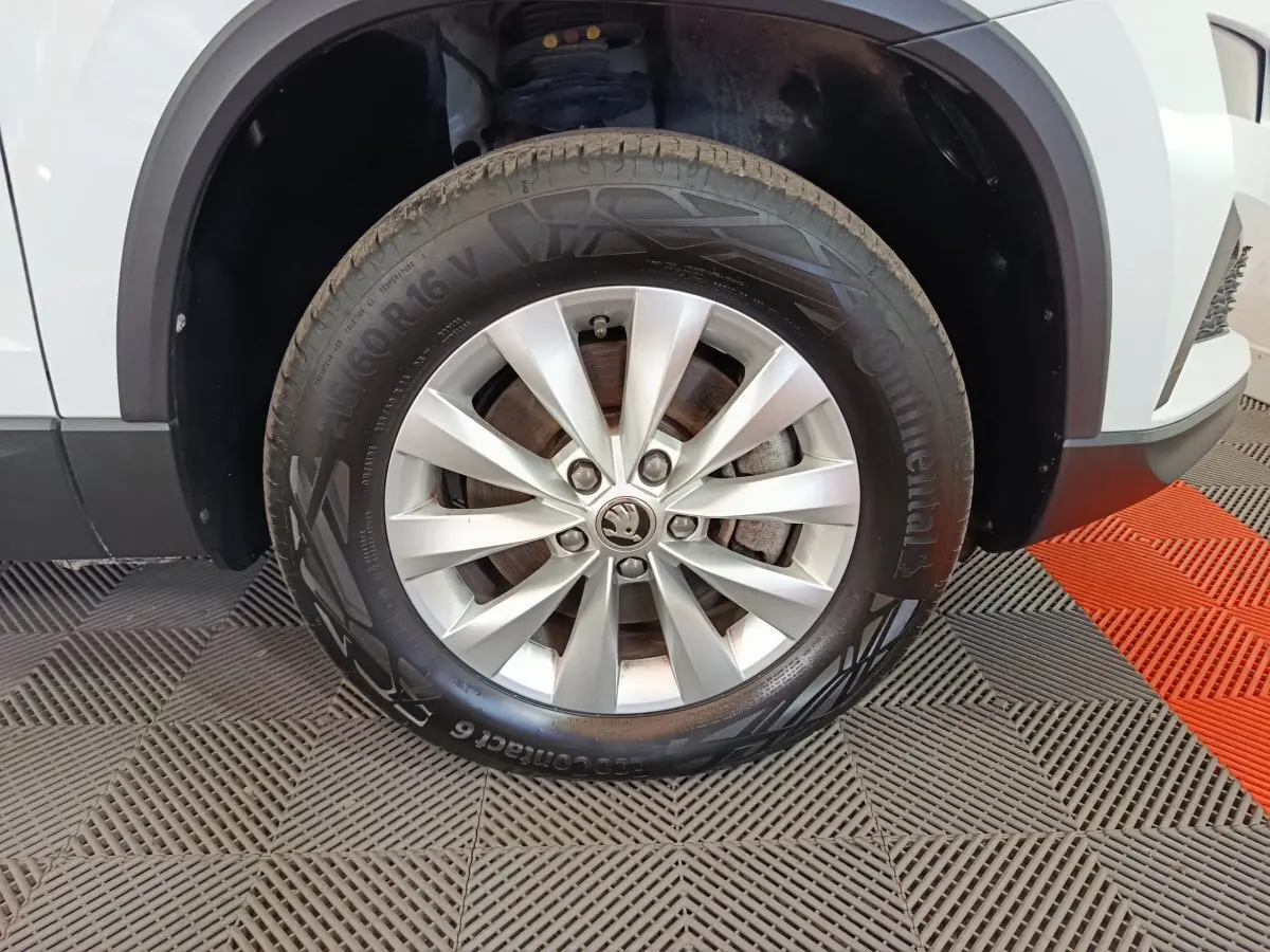 Gros plan sur la roue avant gauche d’un Skoda Karoq blanc 2024 avec jante alliage et pneu Continental.