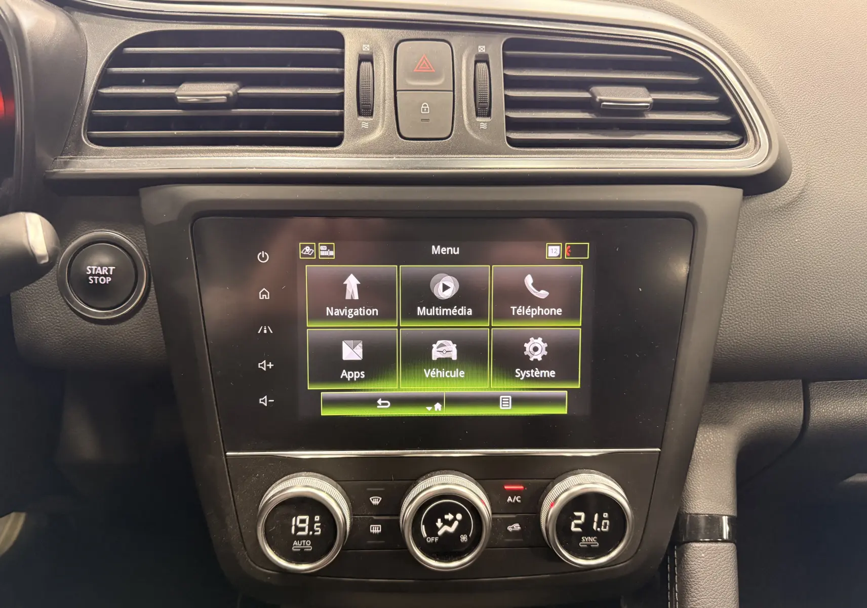 Vue rapprochée de la console centrale du Renault Kadjar blanc, avec écran tactile et commandes de climatisation visibles.