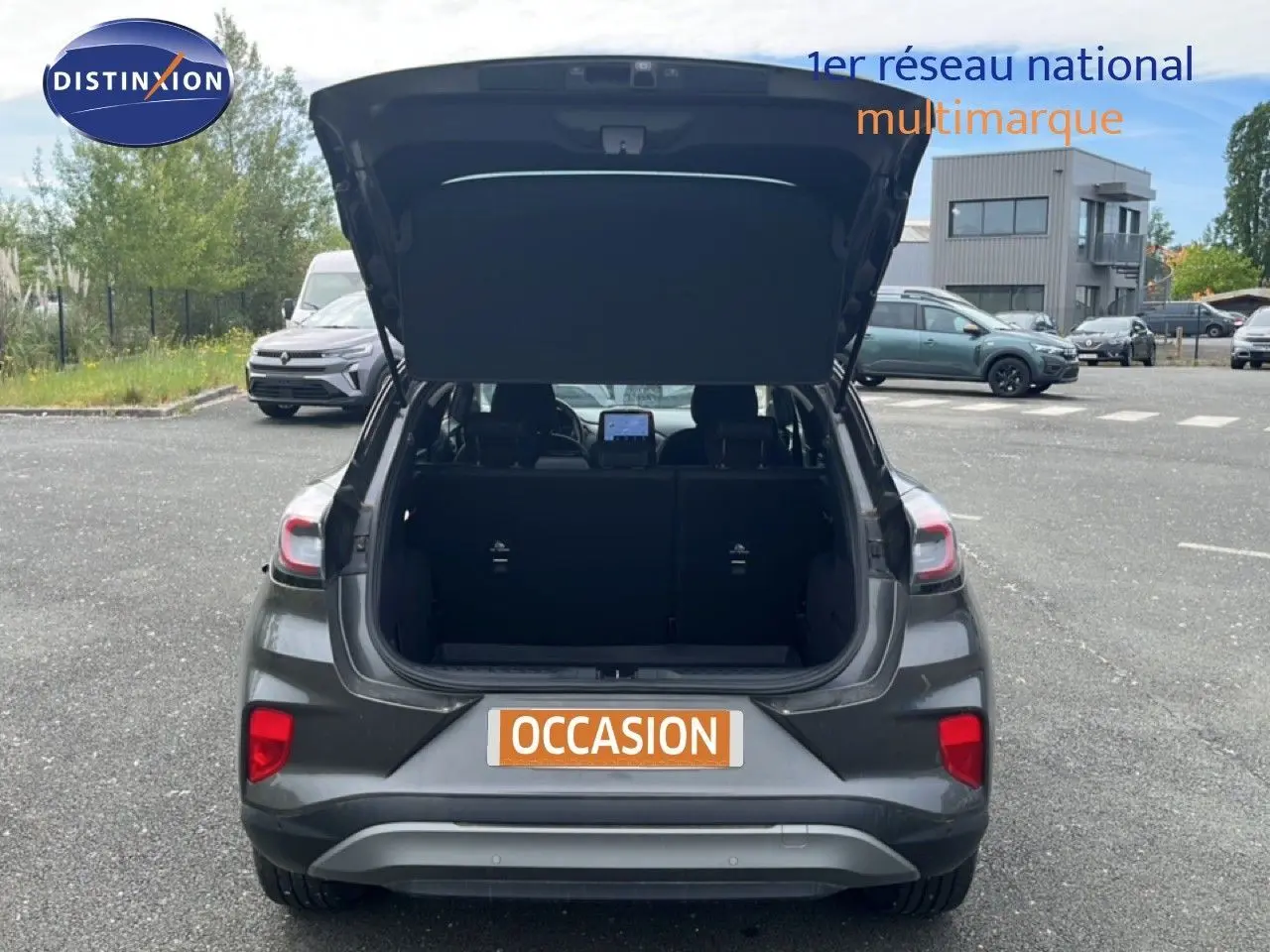 Vue arrière d'un Ford Puma gris 2021 avec coffre ouvert, mettant en valeur les feux arrière et l'espace de chargement.