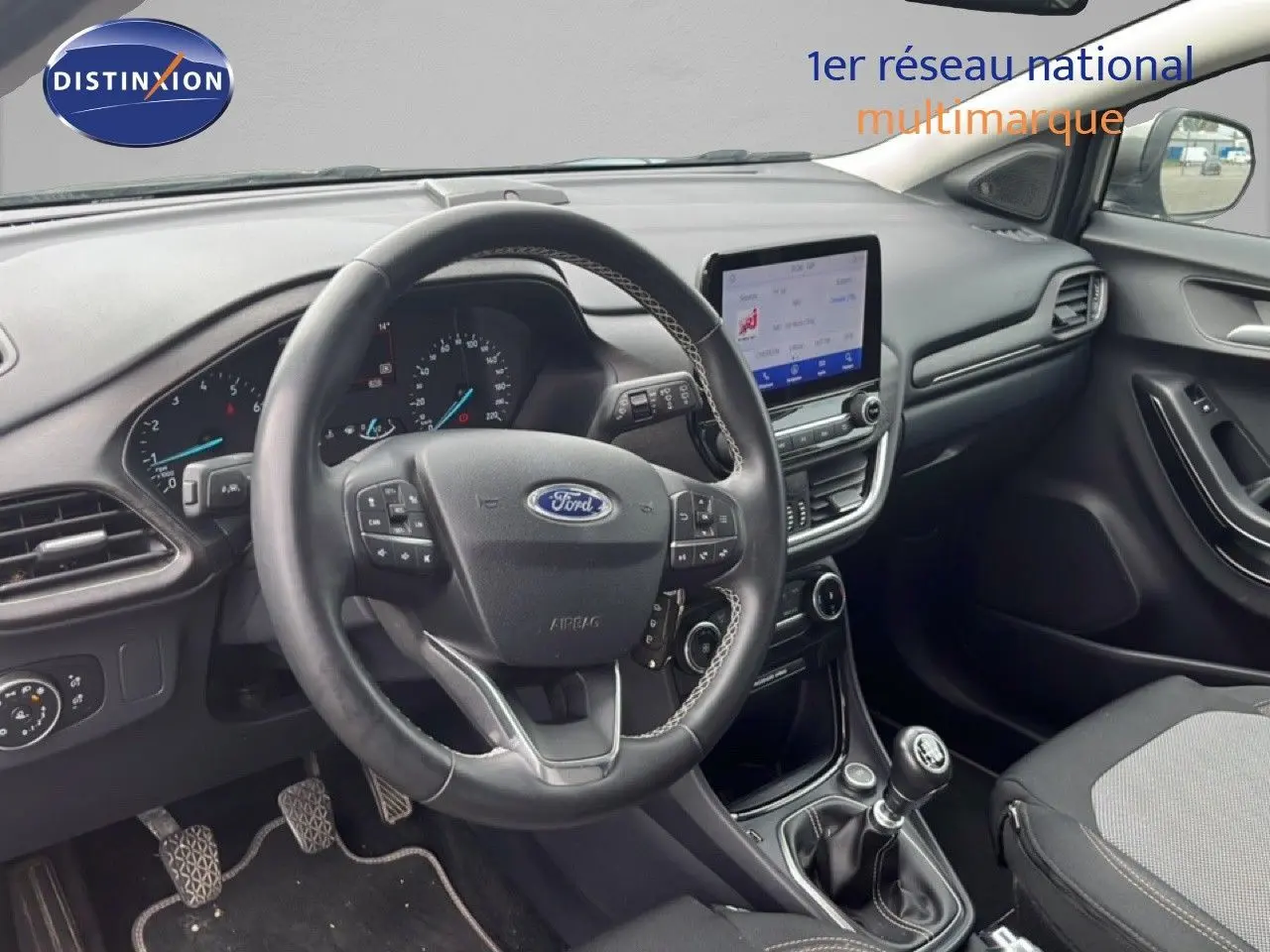 Vue intérieure côté conducteur du Ford Puma gris 2021, mettant en valeur le volant multifonction et la console centrale avec écran tactile.
