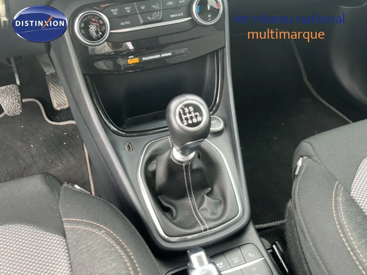 Gros plan sur la console centrale du Ford Puma gris 2021, mettant en valeur la boîte manuelle et les sièges tissu noirs.