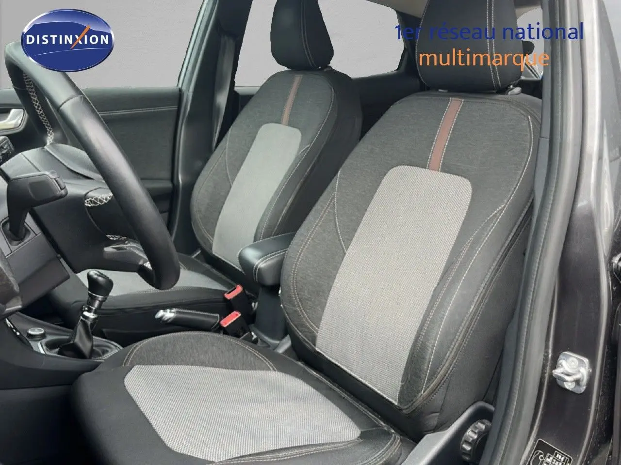 Vue intérieure côté conducteur du Ford Puma gris 2021, montrant les sièges bi-matière et la boîte manuelle.