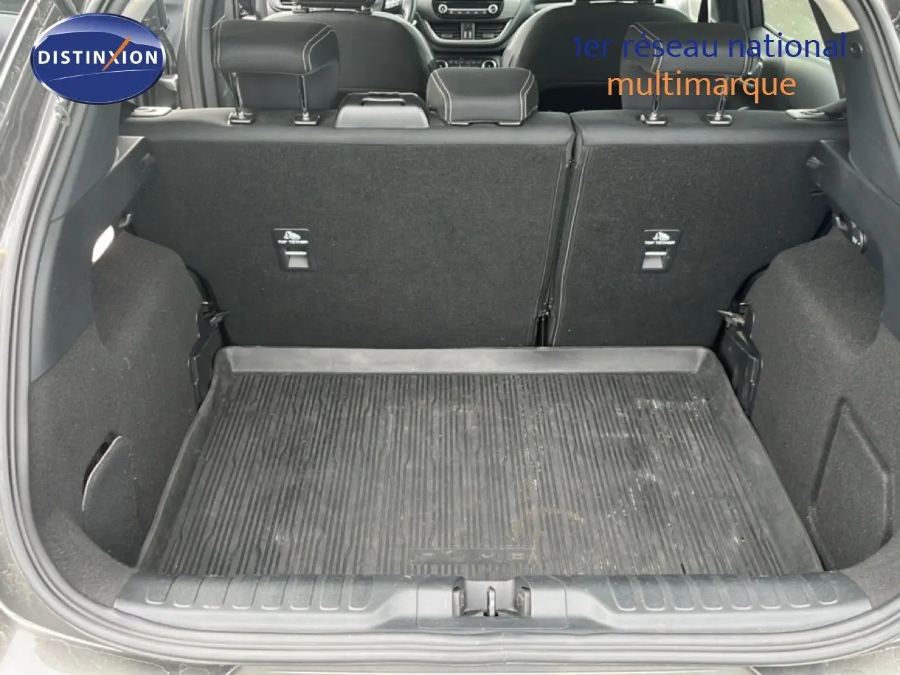 Vue arrière du coffre ouvert du Ford Puma gris 2021, montrant le tapis de sol en caoutchouc et les dossiers de sièges rabattables.