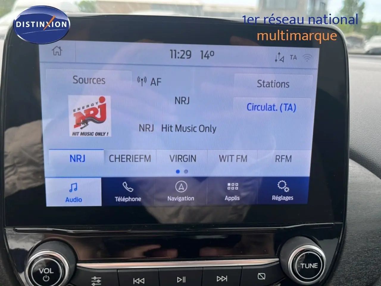 Vue intérieure centrée sur l'écran multimédia du Ford Puma gris 2021 avec interface radio NRJ affichée.