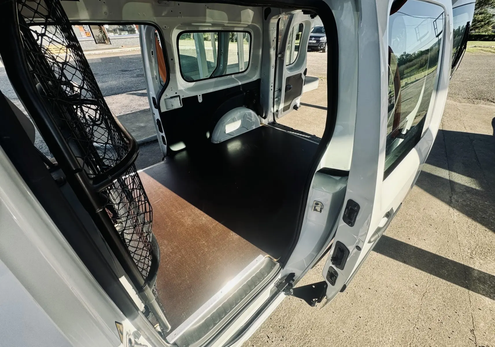 Vue intérieure arrière du Renault Kangoo Maxi blanc 2021, montrant l’espace de chargement avec cloison métallique.