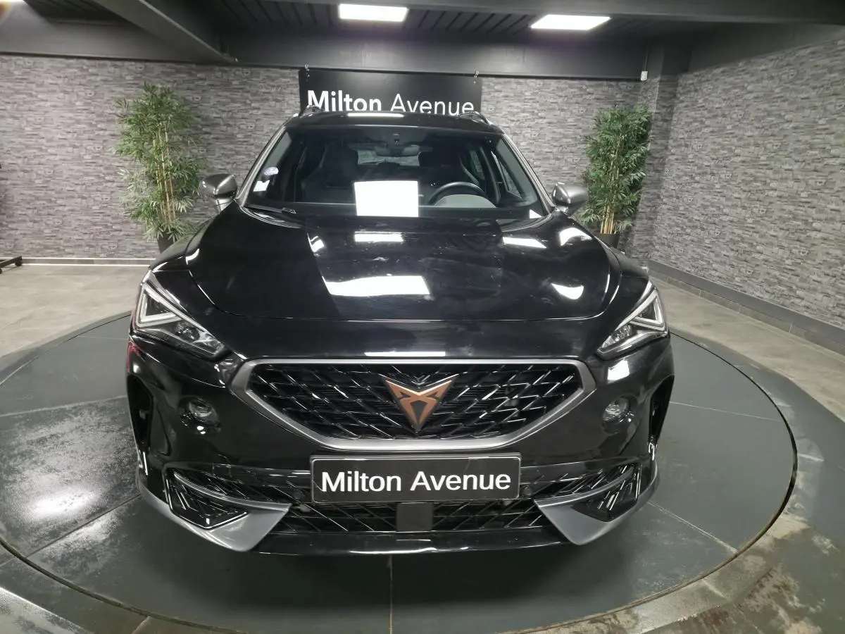 Vue frontale d'un CUPRA Formentor noir Minuit 2023 avec calandre marquée et logo cuivre, dans un showroom intérieur.