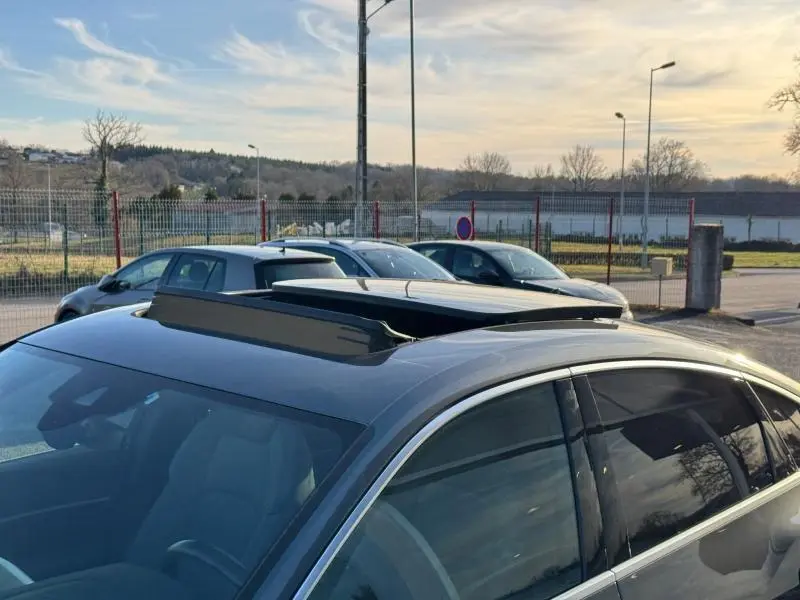 Vue 3/4 avant droit d’un Audi E-Tron Sportback gris foncé métal avec toit ouvrant panoramique ouvert.
