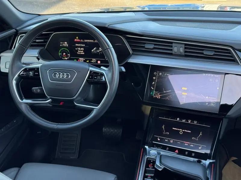 Vue intérieure du tableau de bord et volant cuir multifonction de l'Audi E-Tron Sportback gris foncé, avec écrans tactiles et affichage numérique.