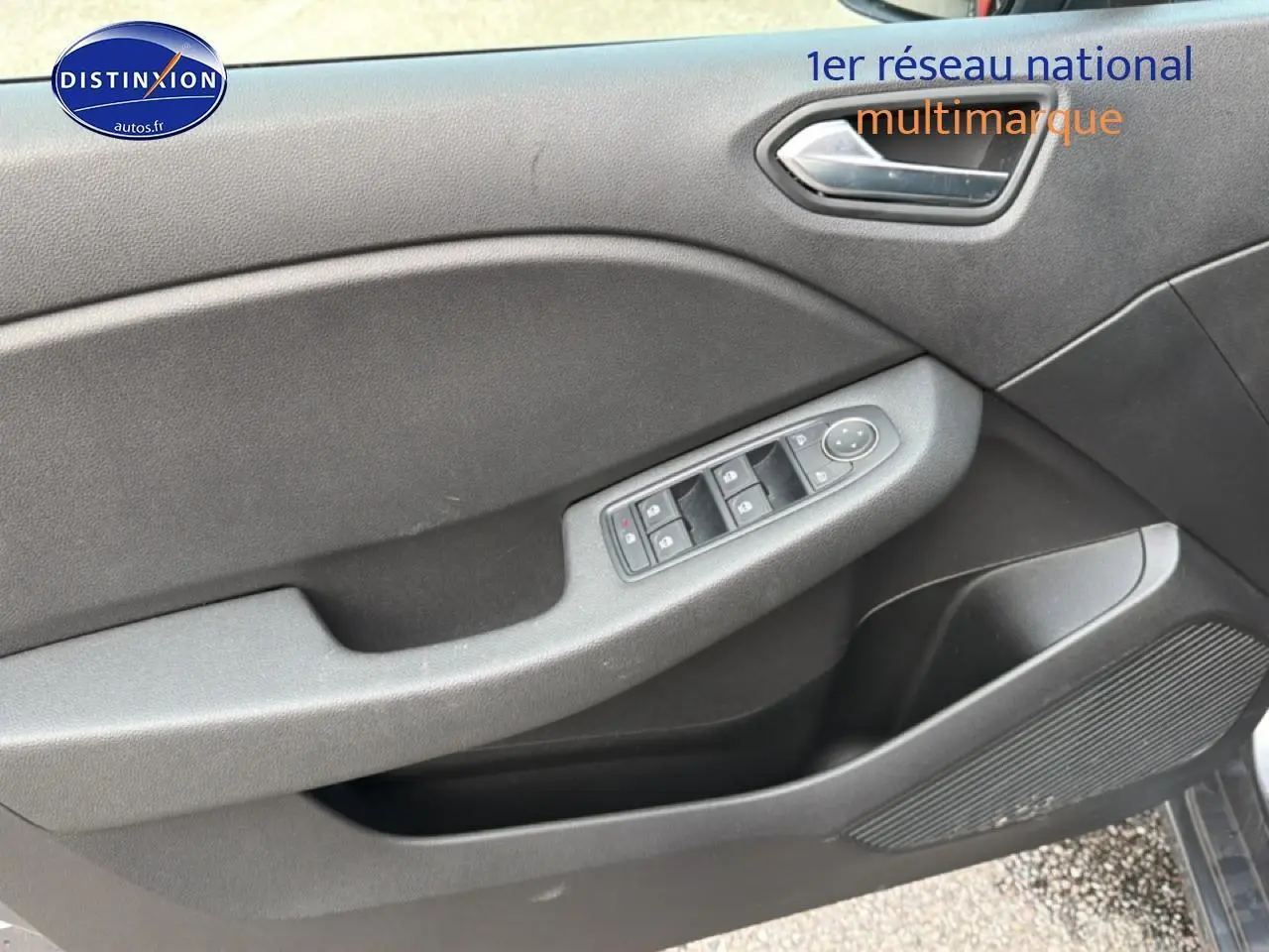 Vue rapprochée de la porte avant gauche de la Renault Clio V gris, montrant les commandes des vitres et haut-parleur intégré.