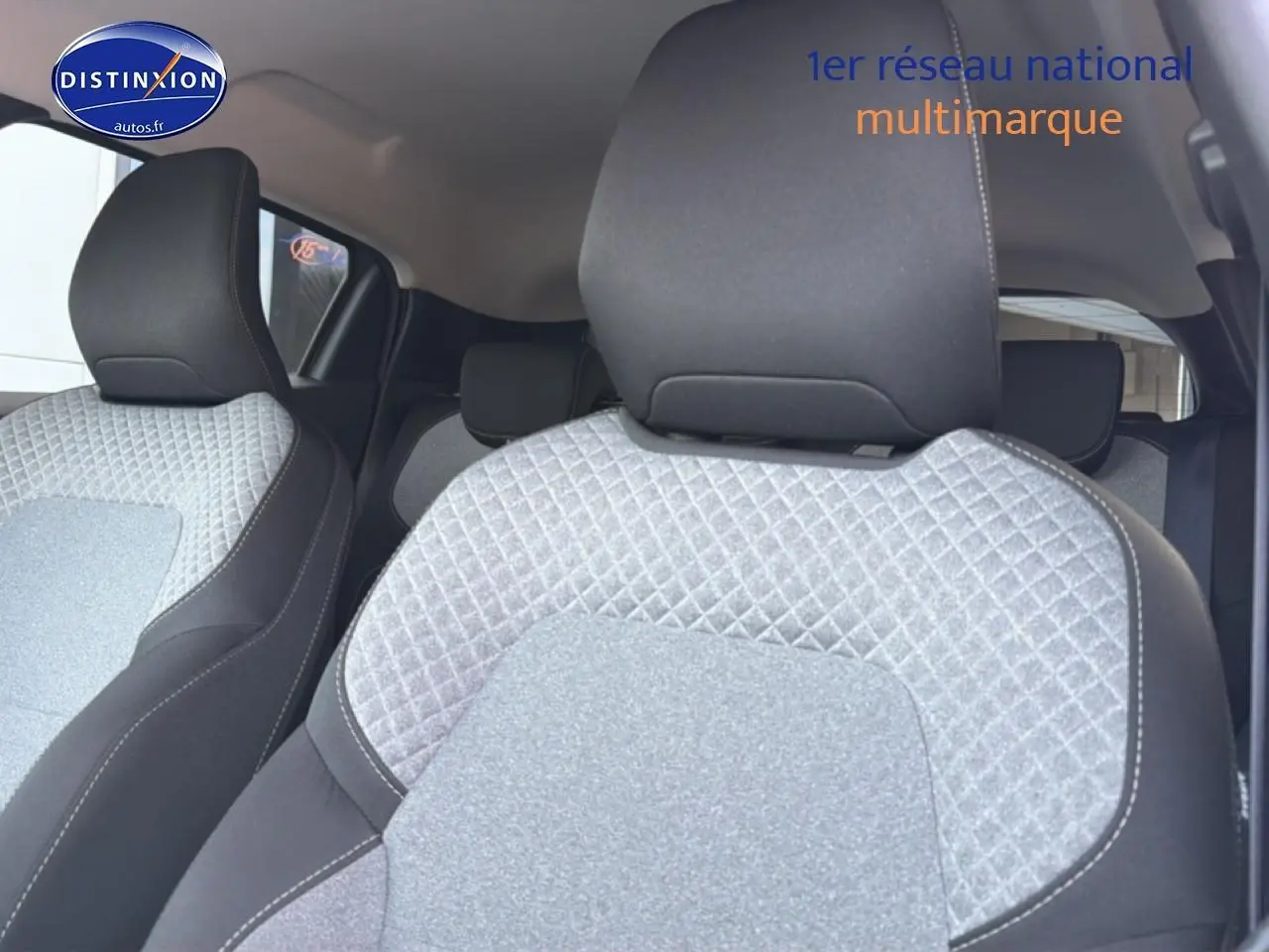 Gros plan sur les sièges avant gris à motif 3D de la Renault Clio V, intérieur textile avec appuie-têtes noirs.