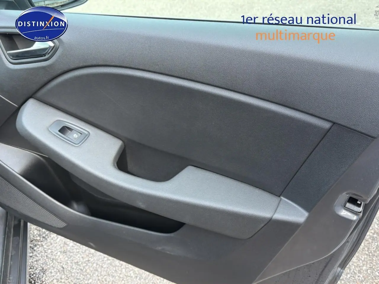 Détail de la porte côté gauche de la Renault Clio V gris, montrant la commande de vitre électrique et le revêtement intérieur noir.