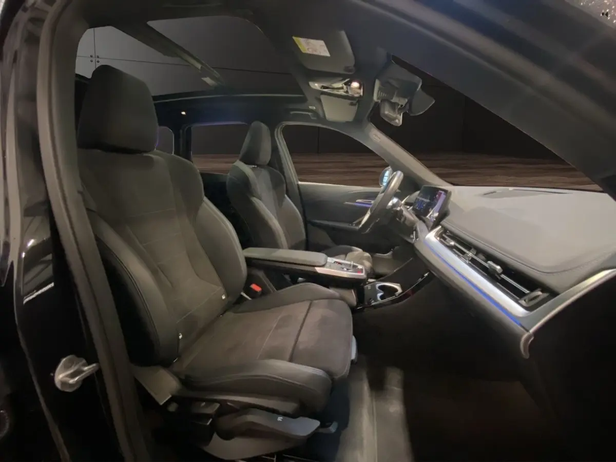 Vue intérieure côté conducteur du BMW X1 noir 2025, mettant en valeur les sièges sport et le tableau de bord moderne avec écran tactile.