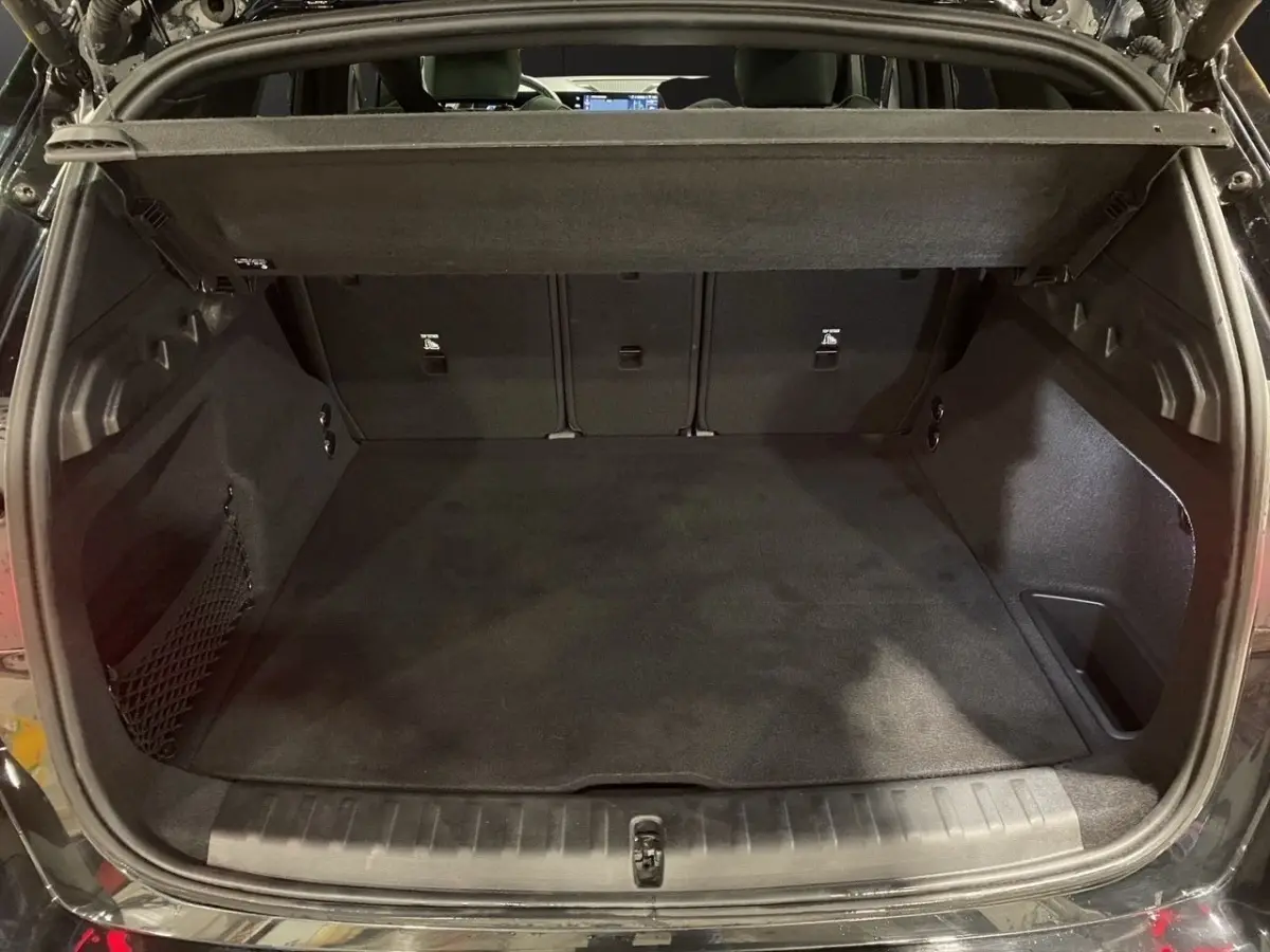 Coffre ouvert vu de l'arrière d'un BMW X1 noir, montrant un espace de chargement propre et spacieux.