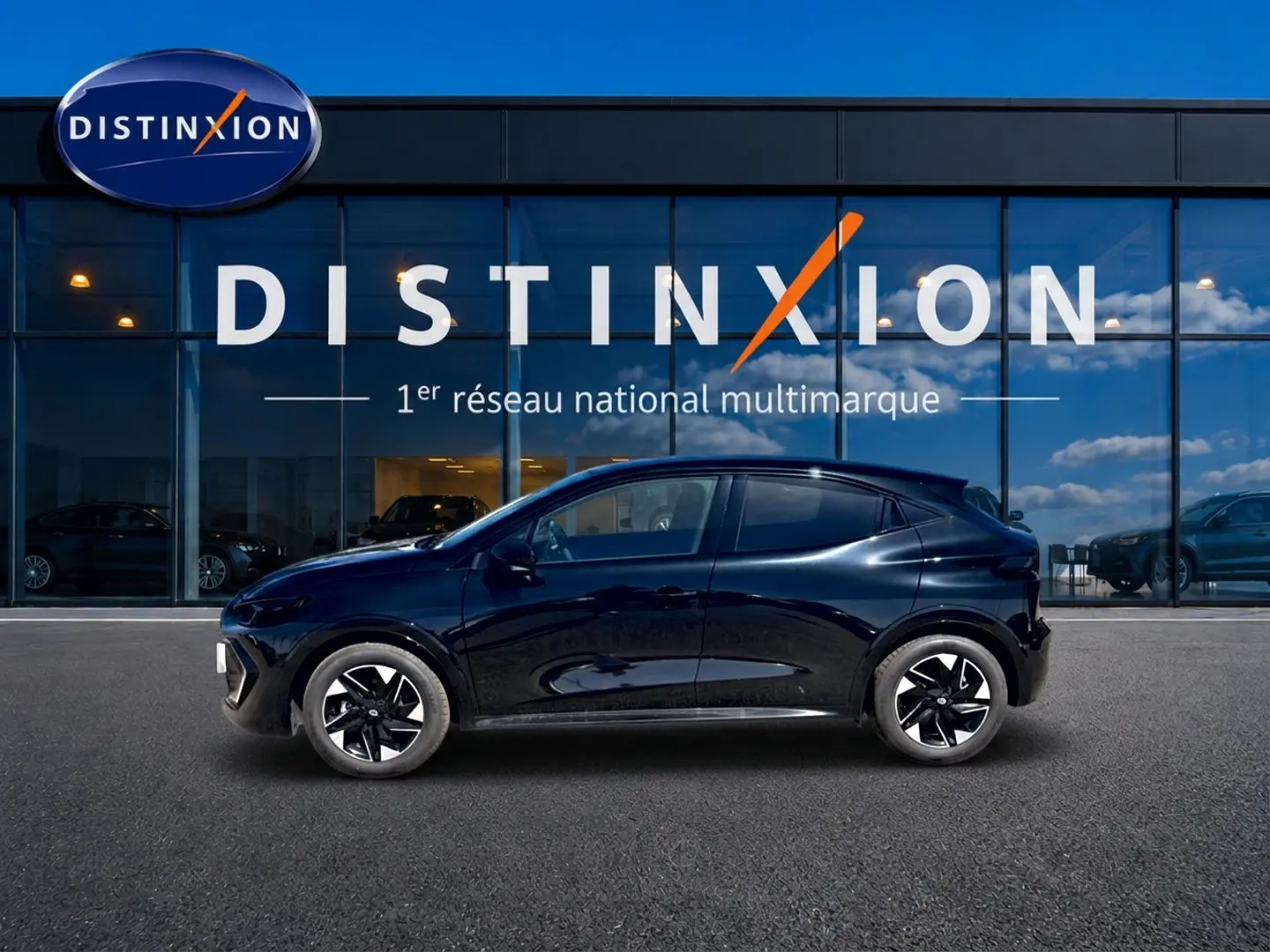 Profil côté gauche de la Renault Clio VI noire 2026, avec jantes alliage 16 pouces, devant une vitrine Distinxion.