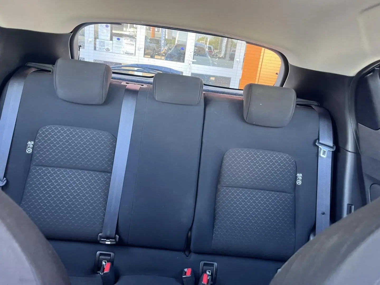 Vue intérieure sur la banquette arrière en tissu noir du Nissan Juke 2023 avec appuis-tête et ceintures de sécurité.