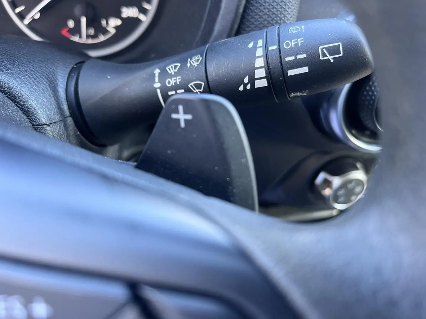 Gros plan sur la commande d'essuie-glace et la palette de changement de vitesse du volant du Nissan Juke 2023.