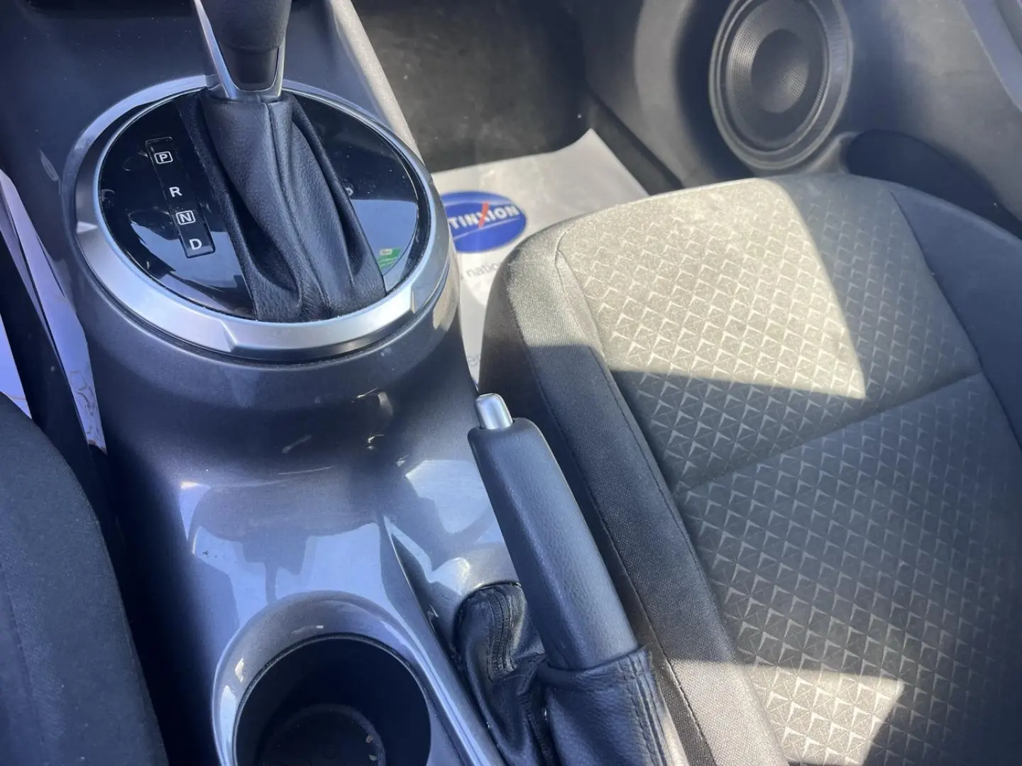 Gros plan sur la console centrale intérieure grise avec levier de boîte auto et siège tissu noir côté passager.