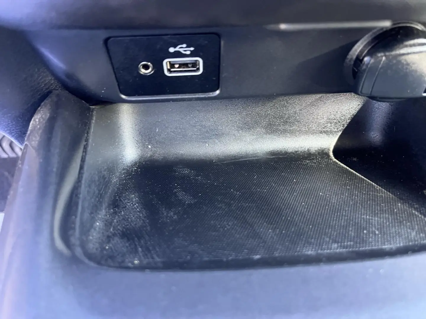 Gros plan sur la prise USB et la prise jack dans le compartiment de rangement intérieur noir du Nissan Juke 2023.