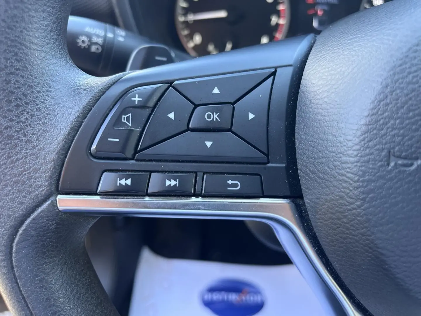 Gros plan sur les commandes multifonctions à gauche du volant du Nissan Juke 2023 en tissu noir.