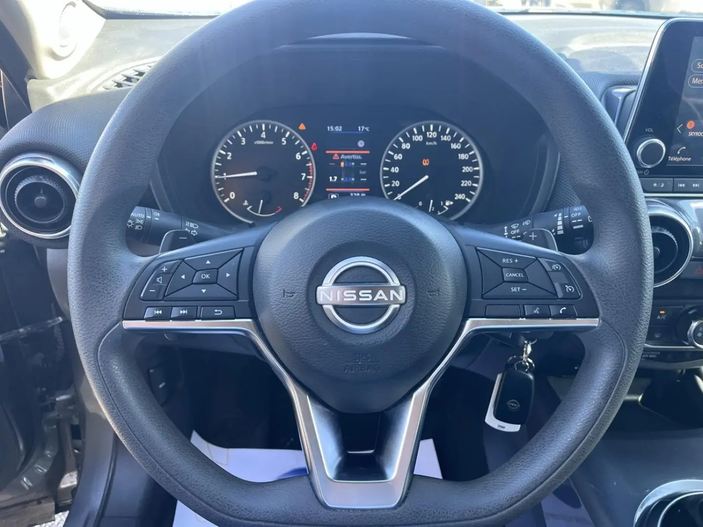 Vue rapprochée du volant multifonction noir et du tableau de bord digital du Nissan Juke 2023 Gris Argile Spéciale.