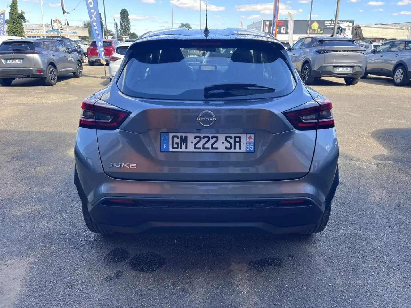 Vue arrière d'un Nissan Juke 2023 gris argile spéciale, avec feux arrière LED et plaque d'immatriculation française visible.