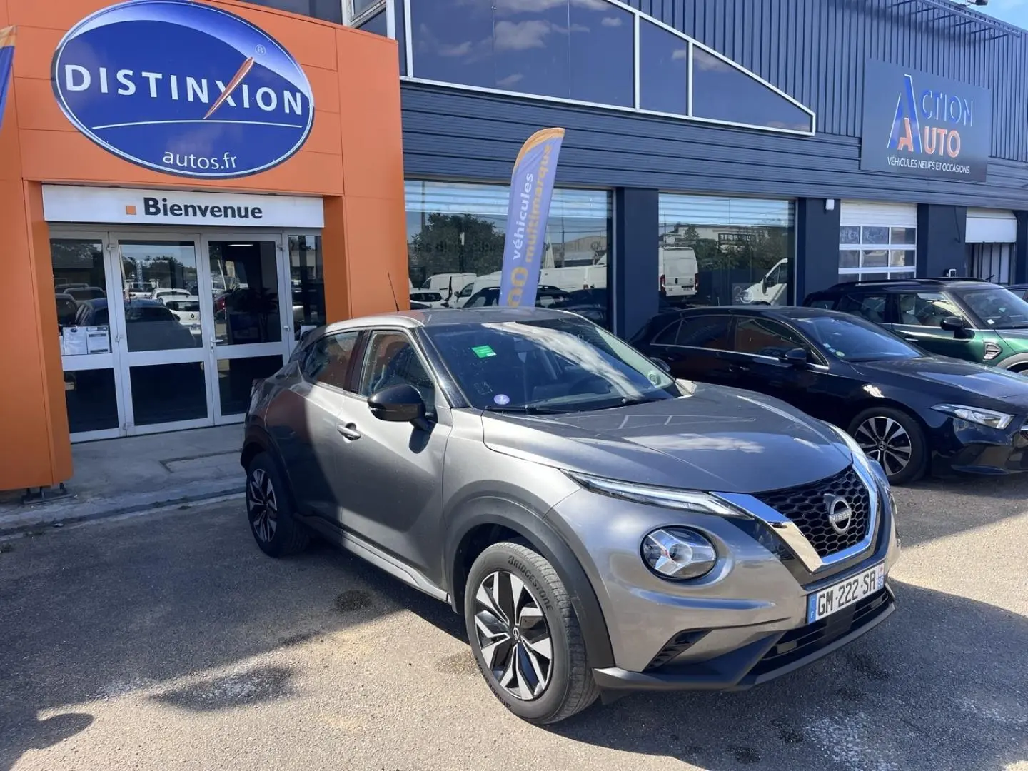 Nissan Juke gris Argile Spéciale vue 3/4 avant droit, avec calandre V-Motion et jantes bi-ton visibles.