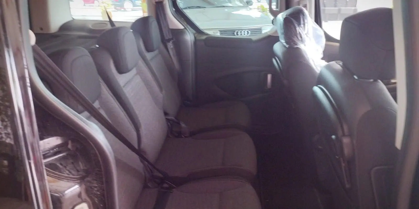 Intérieur arrière du Citroën Berlingo noir 2016, vue côté gauche montrant les trois sièges passagers en tissu gris.