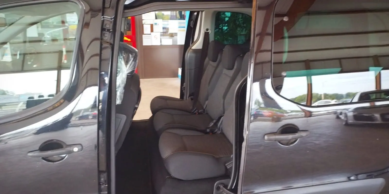 Vue latérale côté droit du Citroën Berlingo noir 2016 avec portes coulissantes ouvertes et sièges arrière visibles.