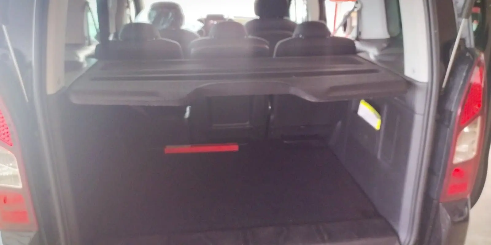 Coffre ouvert d'un Citroën Berlingo noir 2016, vue arrière montrant l'espace de chargement et les sièges arrière.