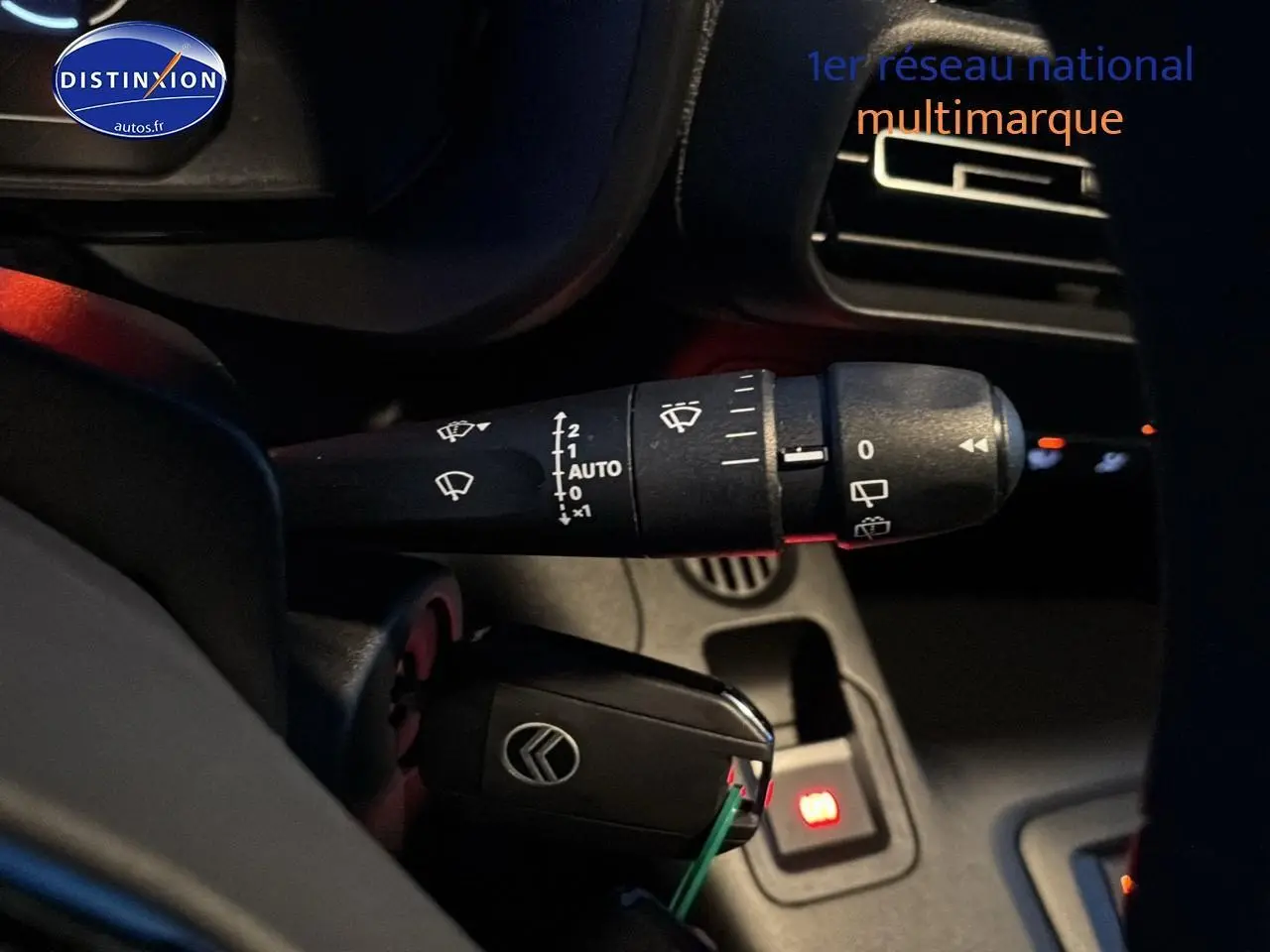 Gros plan sur la commande d’essuie-glace et la clé de contact dans l’habitacle du Citroën Berlingo Fourgon blanc.