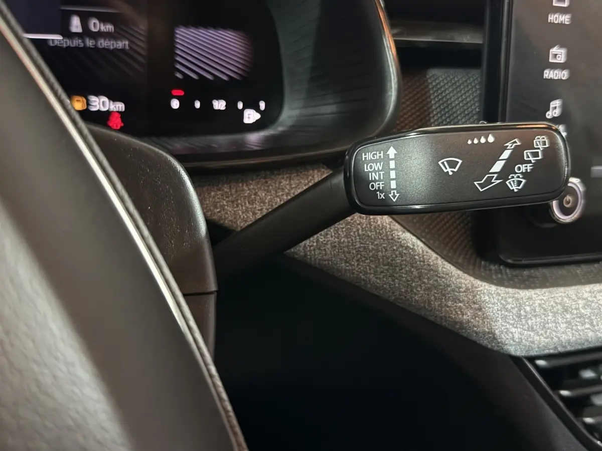 Gros plan sur la commande d’essuie-glace à gauche du volant cuir dans l’habitacle du Skoda Kamiq rouge 2024.