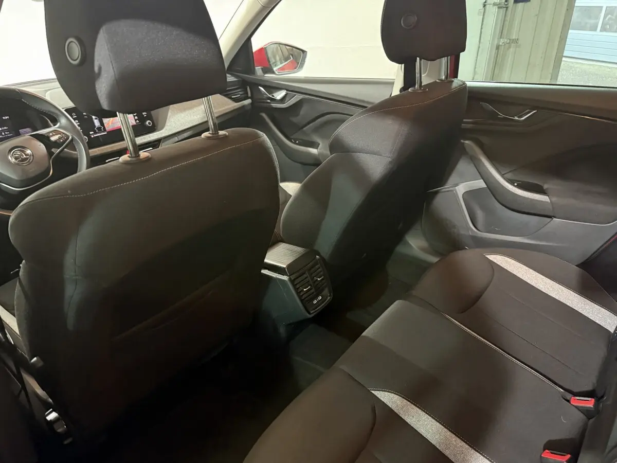 Vue intérieure arrière du Skoda Kamiq 2024 avec sièges noirs et console centrale avec aérateurs et ports USB.