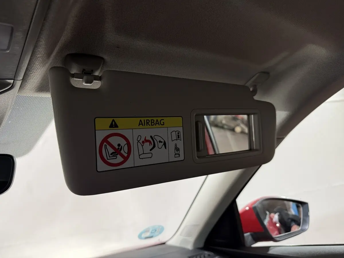 Vue intérieure du pare-soleil côté conducteur avec miroir et rétroviseur extérieur rouge visible d’un Skoda Kamiq 2024.