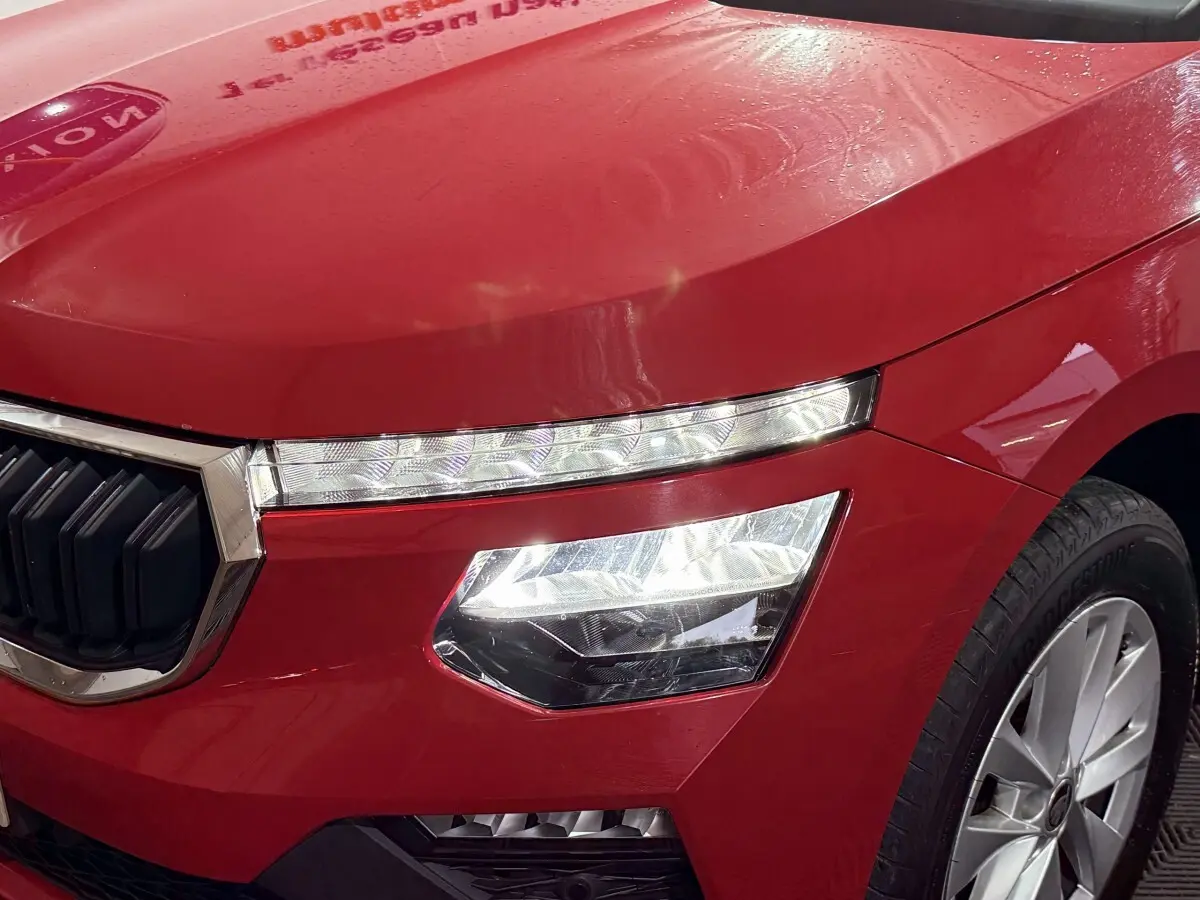 Gros plan sur l’avant droit rouge vif du Skoda Kamiq 2024, mettant en valeur ses phares LED et la calandre chromée.